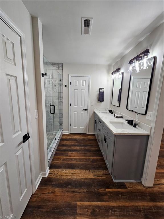 bathroom featuring wood-type flooring, vanity, and a shower with door