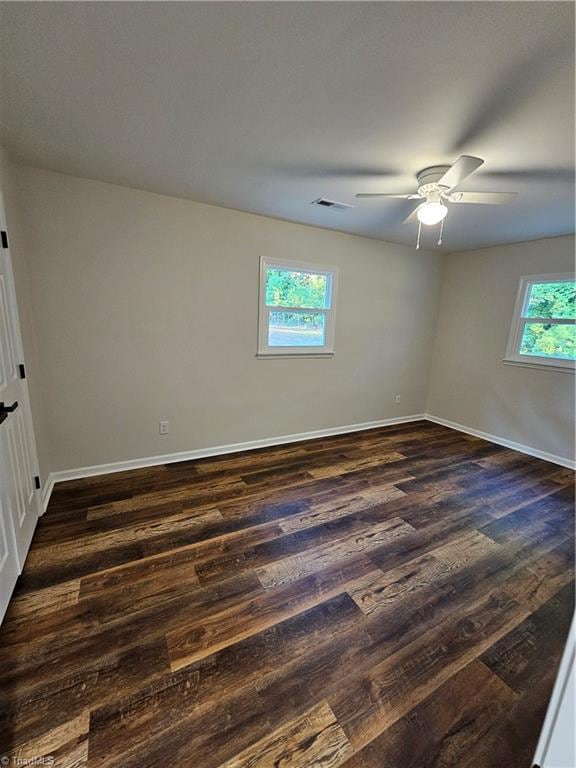 spare room with dark hardwood / wood-style flooring, ceiling fan, and a wealth of natural light