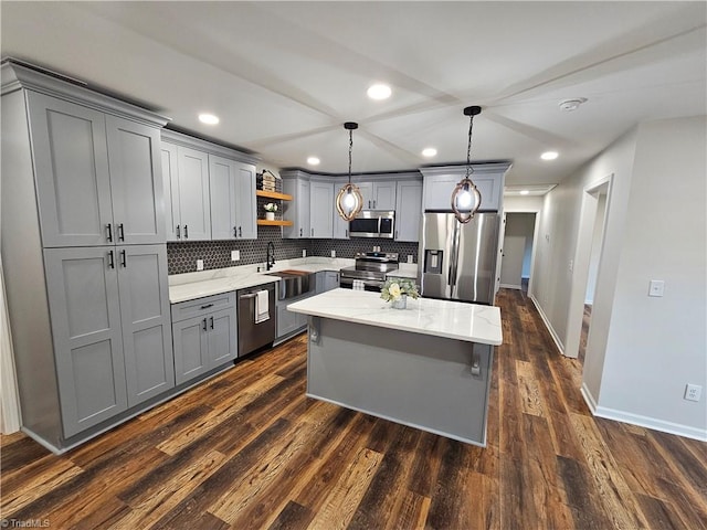 kitchen featuring appliances with stainless steel finishes, gray cabinetry, backsplash, pendant lighting, and dark hardwood / wood-style floors