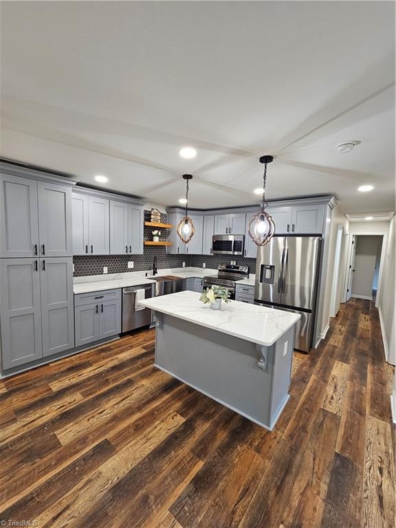 kitchen featuring dark wood-type flooring, gray cabinetry, stainless steel appliances, backsplash, and decorative light fixtures