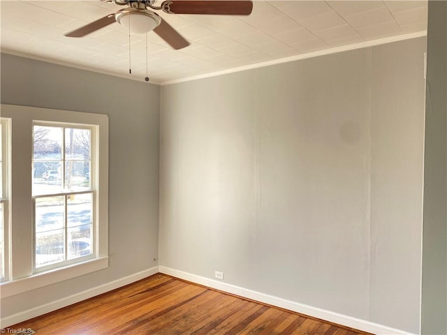 spare room with a ceiling fan, crown molding, baseboards, and wood finished floors