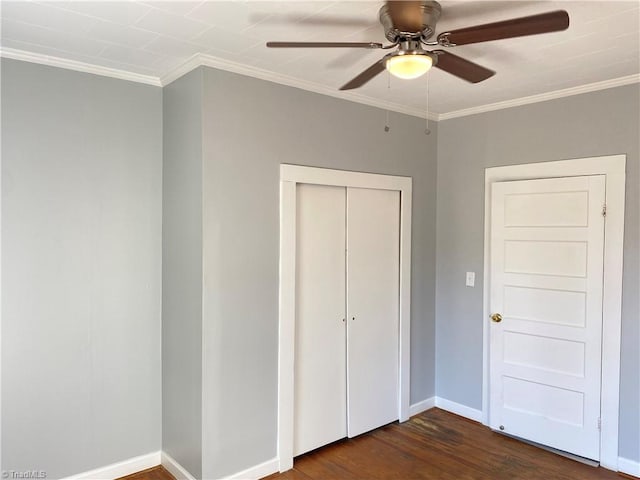 unfurnished bedroom featuring dark wood-type flooring, a closet, crown molding, and baseboards