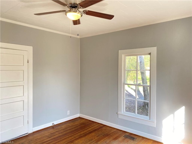 empty room with crown molding, visible vents, ceiling fan, wood finished floors, and baseboards