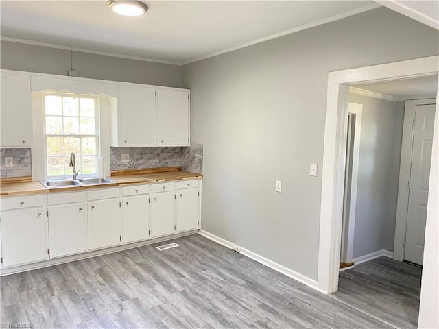 kitchen with crown molding, backsplash, and a sink