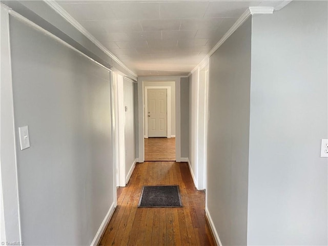 hallway featuring ornamental molding, visible vents, baseboards, and hardwood / wood-style flooring