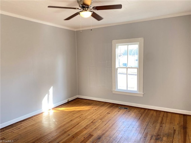 unfurnished room featuring ornamental molding, wood-type flooring, visible vents, and baseboards