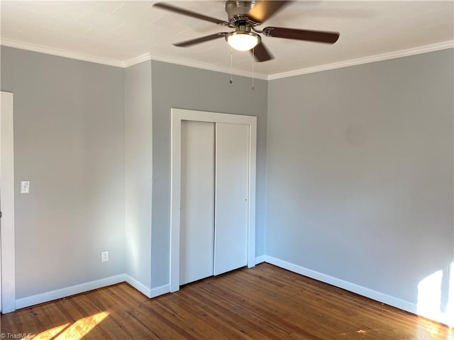 unfurnished bedroom with dark wood-style floors, a closet, baseboards, and crown molding