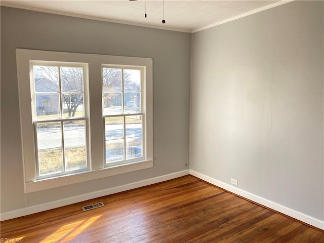 spare room with plenty of natural light, wood-type flooring, ornamental molding, and baseboards