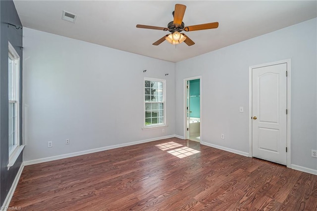 empty room with a ceiling fan, visible vents, wood finished floors, and baseboards