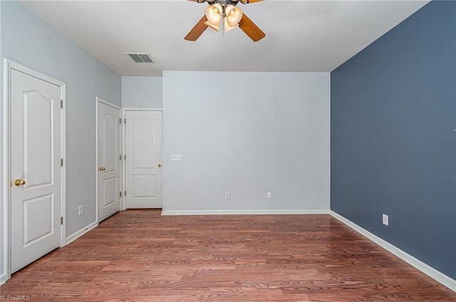 unfurnished bedroom featuring visible vents, ceiling fan, baseboards, and wood finished floors