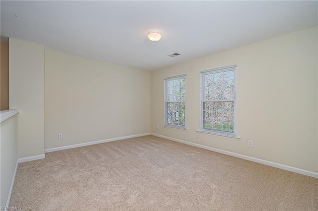 unfurnished room with baseboards, visible vents, and light carpet