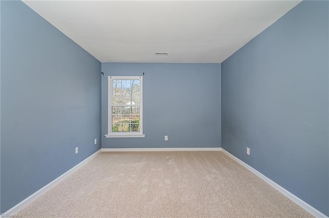 empty room with carpet flooring, baseboards, and visible vents