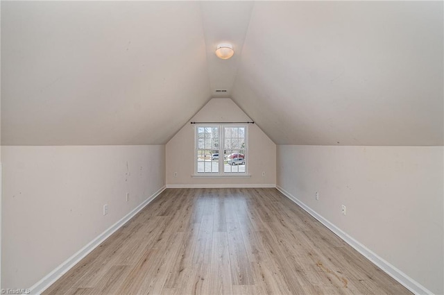 additional living space featuring lofted ceiling, light wood-style flooring, and baseboards