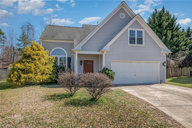 traditional home featuring a front lawn, fence, concrete driveway, roof with shingles, and a garage