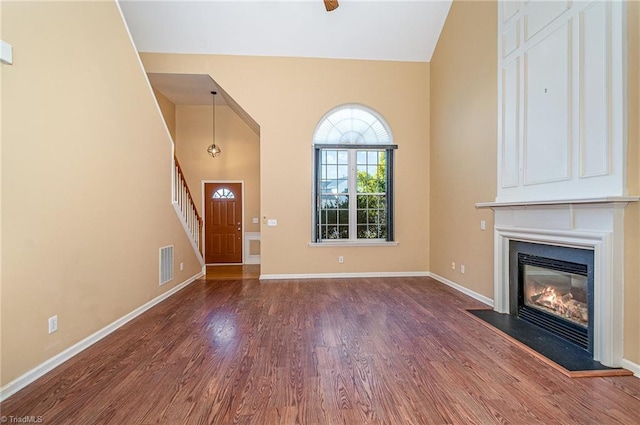 entryway featuring a glass covered fireplace, visible vents, wood finished floors, and stairway