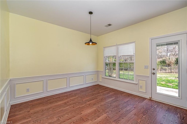 unfurnished dining area with a wealth of natural light, a wainscoted wall, visible vents, and wood finished floors