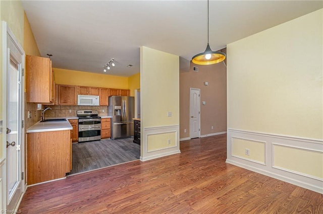 kitchen featuring a sink, appliances with stainless steel finishes, wood finished floors, and light countertops