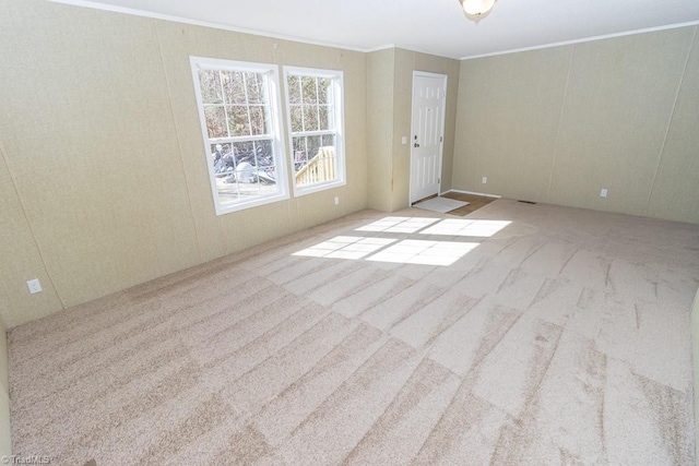 empty room featuring ornamental molding and light carpet