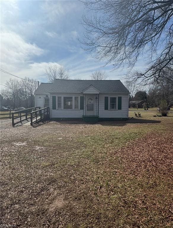 view of front of home featuring fence, a front lawn, and roof with shingles