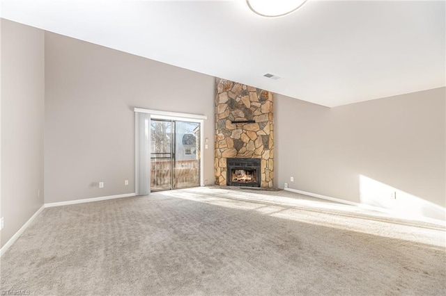 unfurnished living room with visible vents, carpet flooring, vaulted ceiling, a stone fireplace, and baseboards