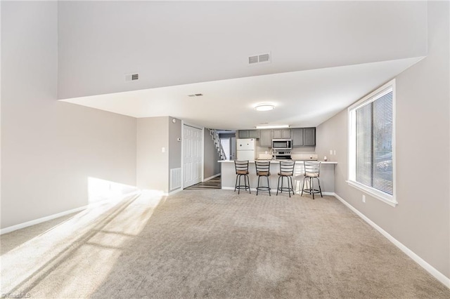 kitchen featuring visible vents, appliances with stainless steel finishes, a breakfast bar area, light countertops, and gray cabinetry