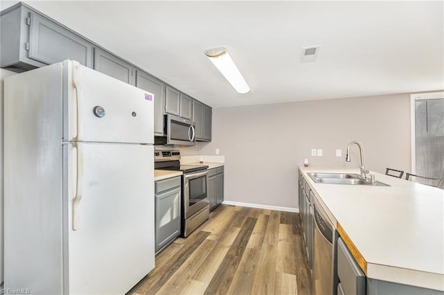 kitchen featuring appliances with stainless steel finishes, a sink, and gray cabinetry