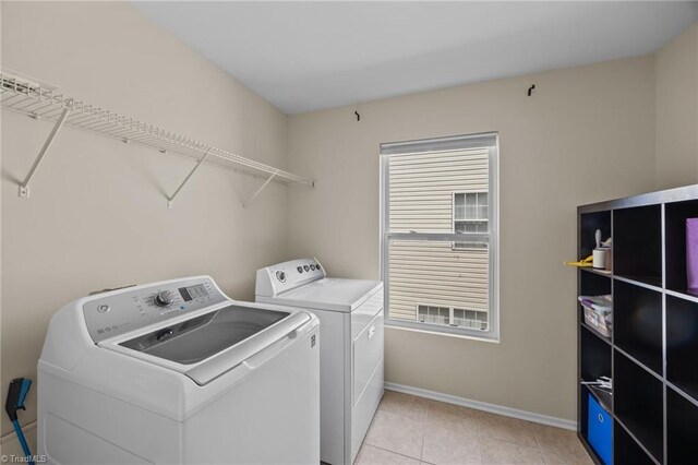 washroom featuring independent washer and dryer, baseboards, and light tile patterned floors