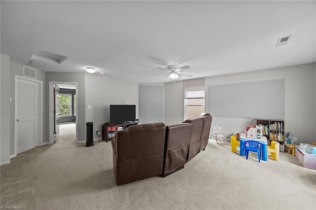 carpeted cinema room with a ceiling fan and baseboards