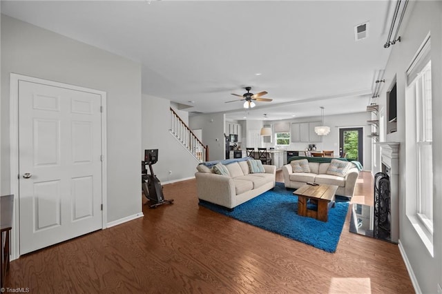 living room with wood finished floors, ceiling fan, stairway, baseboards, and a fireplace