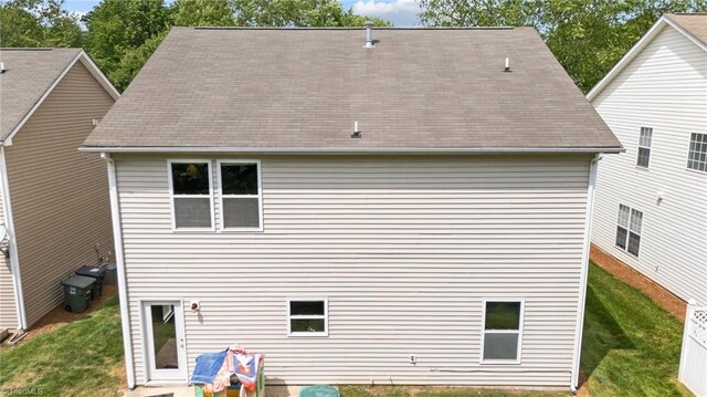 back of property featuring a lawn and roof with shingles
