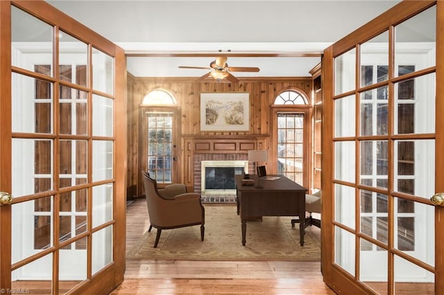 office featuring light hardwood / wood-style flooring, a fireplace, french doors, and wooden walls