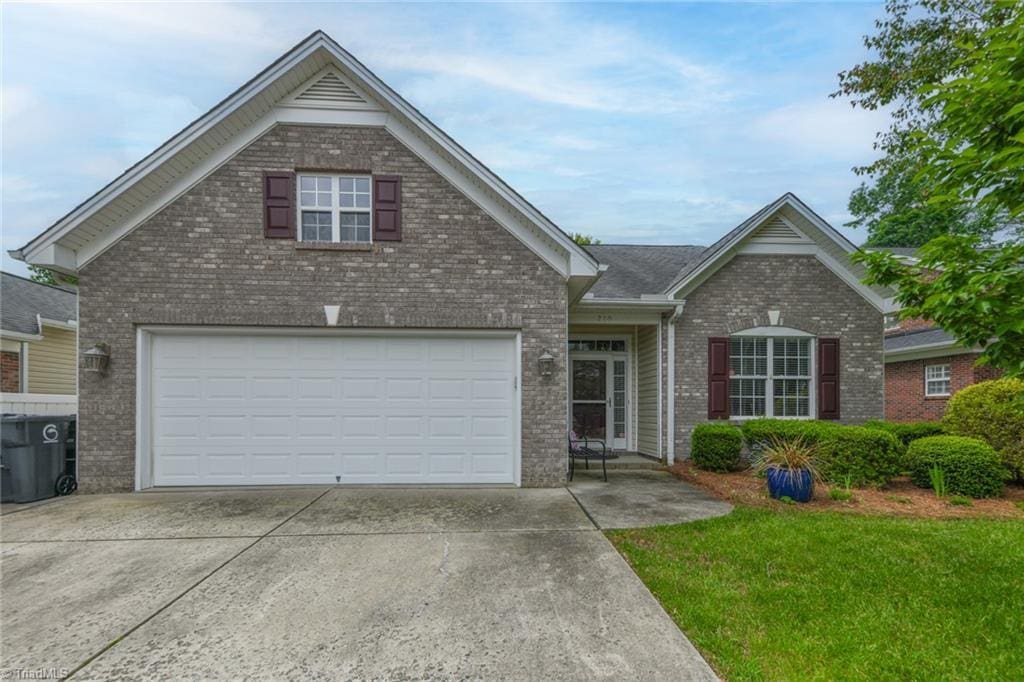210 Heritage Hill Dr, Jamestown, NC 27262 - view of front of property with brick siding, driveway, a garage, and a front lawn