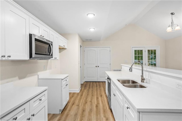 kitchen featuring a sink, white cabinetry, stainless steel appliances, light wood finished floors, and light countertops