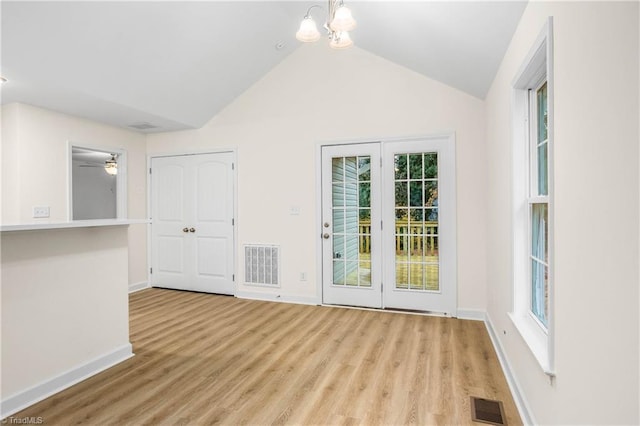 interior space with vaulted ceiling, light wood-style floors, visible vents, and baseboards