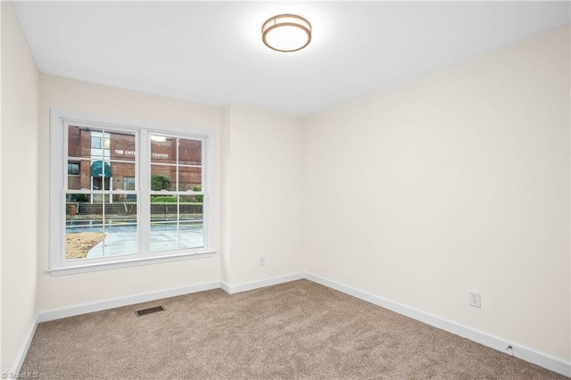 unfurnished room with carpet flooring, visible vents, and baseboards