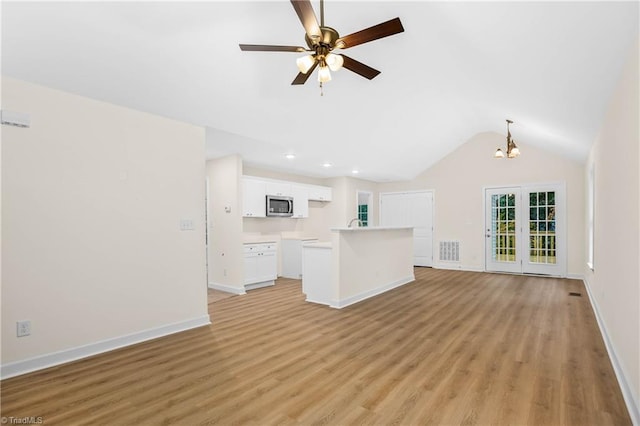 unfurnished living room with visible vents, baseboards, lofted ceiling, light wood-style floors, and ceiling fan with notable chandelier