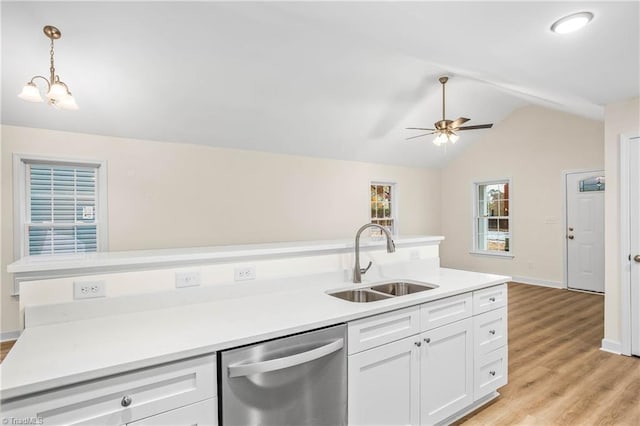 kitchen with dishwasher, vaulted ceiling, ceiling fan with notable chandelier, white cabinetry, and a sink