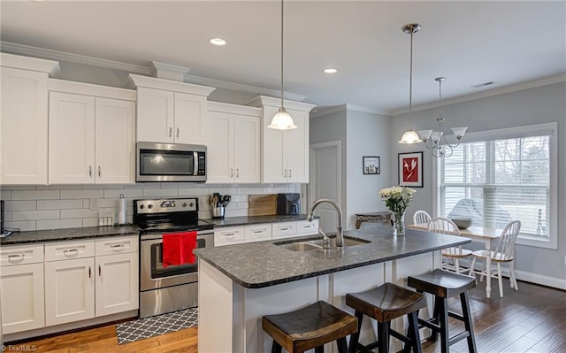 kitchen featuring stainless steel appliances, wood finished floors, a sink, and tasteful backsplash