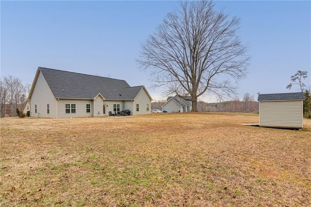 rear view of house with a yard, a storage unit, and an outbuilding