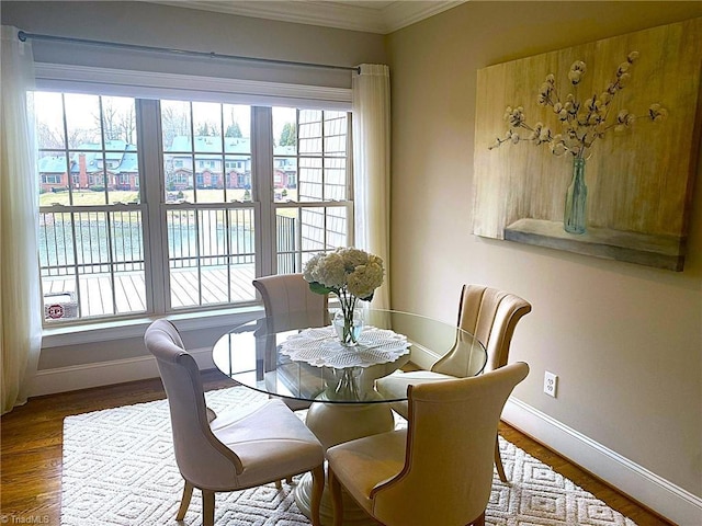 dining space with crown molding, baseboards, and wood finished floors