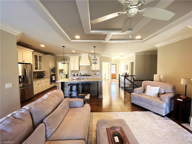 living area with a tray ceiling, recessed lighting, ceiling fan, ornamental molding, and dark wood-type flooring