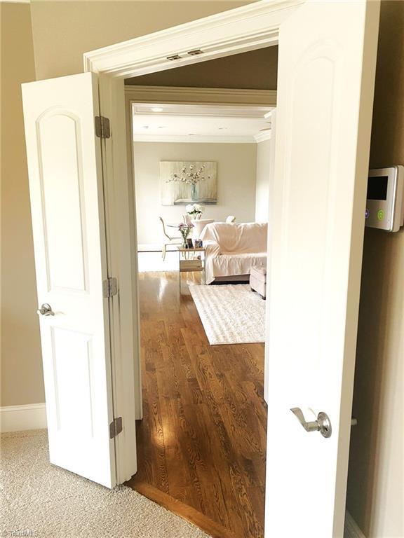 corridor featuring crown molding, wood finished floors, and visible vents