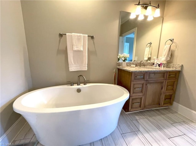 full bathroom featuring vanity, a soaking tub, and baseboards