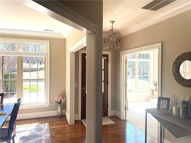 entrance foyer with baseboards, visible vents, an inviting chandelier, dark wood-style flooring, and crown molding