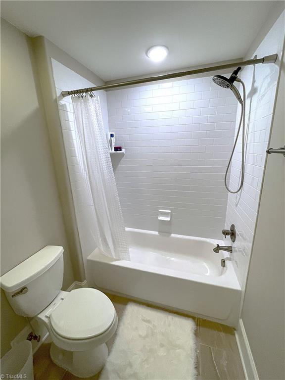 bathroom featuring toilet and shower / tub combo with curtain