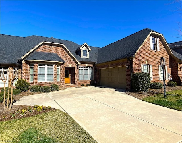 view of front facade featuring driveway, brick siding, an attached garage, and a shingled roof