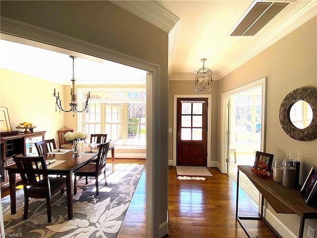 entrance foyer featuring an inviting chandelier, crown molding, dark wood-style floors, and visible vents