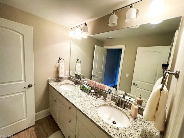 full bath featuring double vanity, visible vents, baseboards, and a sink