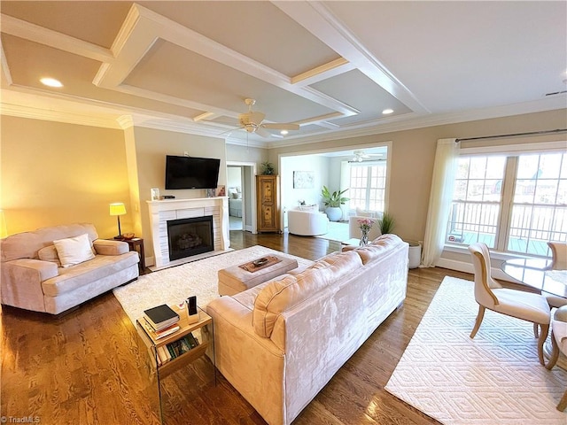 living area with dark wood-type flooring, a ceiling fan, coffered ceiling, and ornamental molding