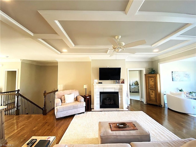 living area featuring dark wood-type flooring, ceiling fan, crown molding, and a tile fireplace